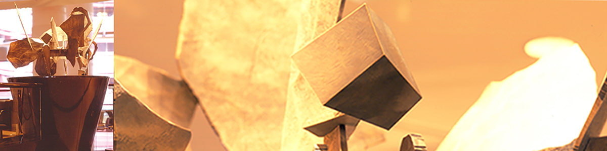 左右の曲線を描く階段の始まりにある逆円錐台のステージに植物が円状に連なった1対のブロンズ色の鋳物彫刻